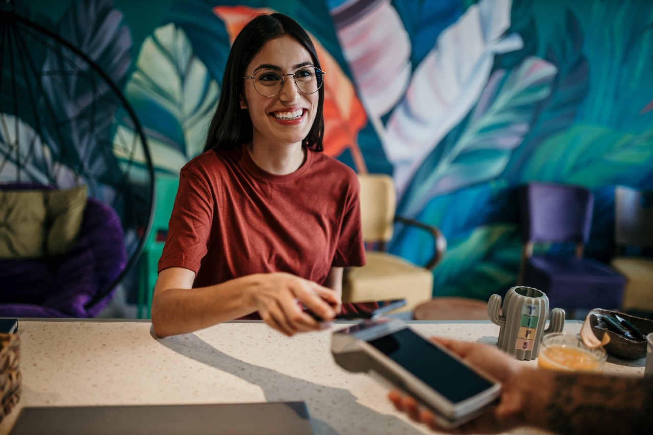 A customer using her phone to make a quick payment at the cafe